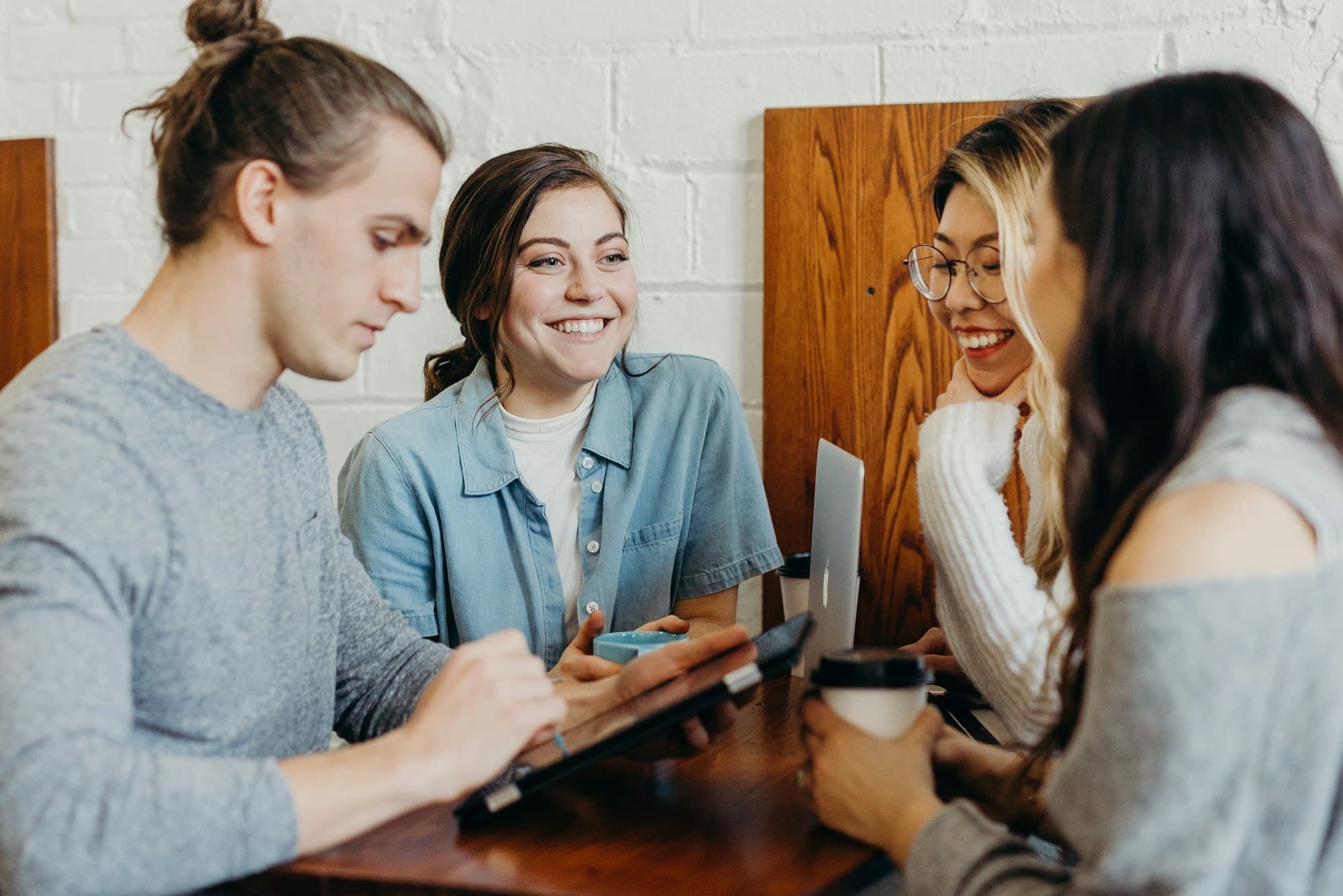 Four adults collaborating around a table with a laptop and coffee