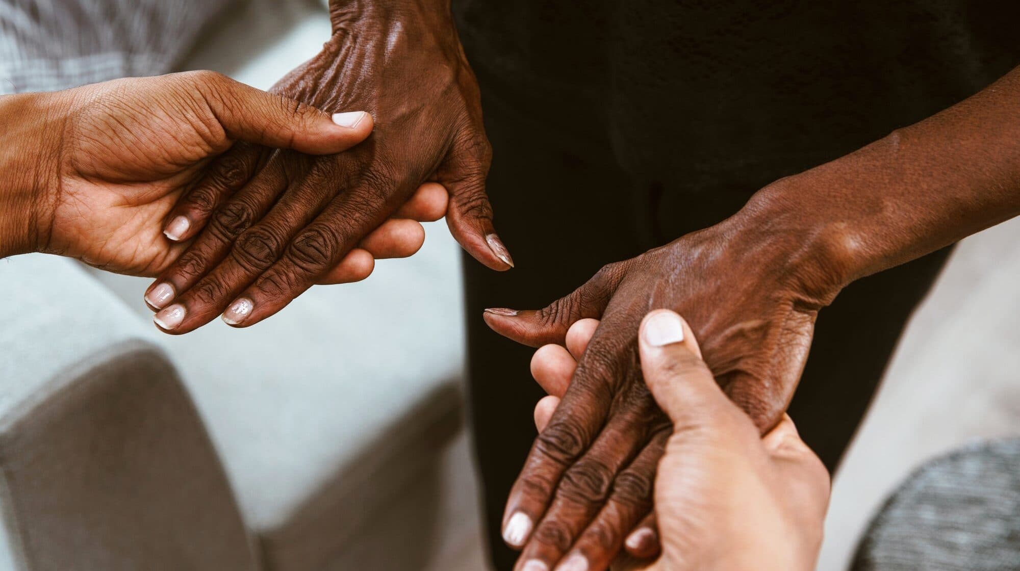 Younger hands gently holding an older person's hands